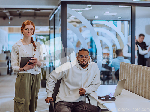 Image of In a modern office African American young businessman and his businesswoman colleague, with her striking orange hair, engage in collaborative problem-solving sessions