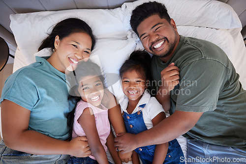 Image of A happy black family in bed, mom and dad hold children with love. In their bedroom at home, little kids laugh as parents hug them with a smile on their faces and enjoy the quality time home together