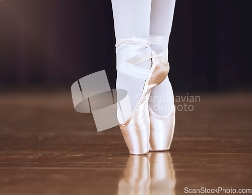 Image of Ballet, dance and shoes with the feet of a ballerina or dancer dancing on a theater stage for a performance or show. Creative, art and training with an artist or performer practicing for a rehearsal