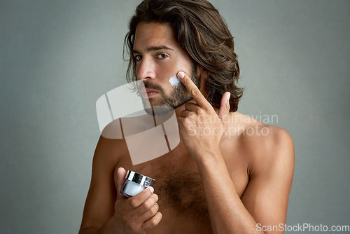 Image of Portrait, beauty or lotion with a shirtless man in studio on a gray background for his grooming routine. Skincare, facial and and the body of a handsome young person with antiaging cream for his skin