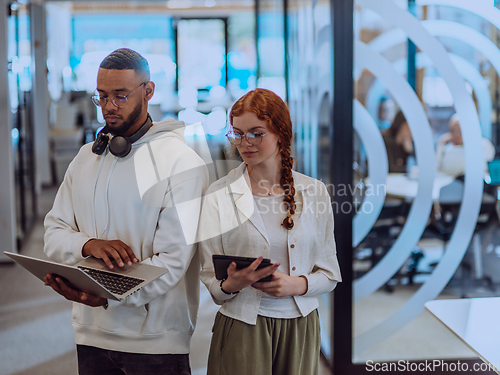 Image of In a modern office African American young businessman and his businesswoman colleague, with her striking orange hair, engage in collaborative problem-solving sessions