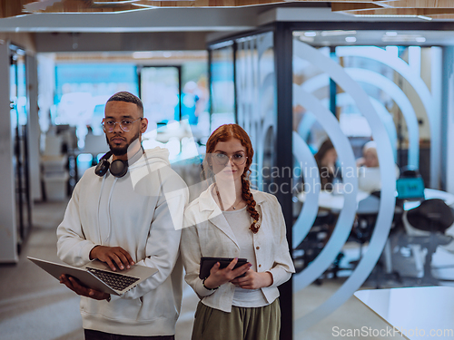 Image of In a modern office African American young businessman and his businesswoman colleague, with her striking orange hair, engage in collaborative problem-solving sessions