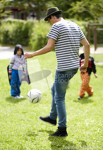 Image of Kindergarten, teacher and playing football with children on grass, lawn or field with game or sport. Soccer, ball or kids with man training to kick or play on playground with fun exercise or activity