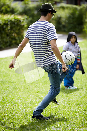 Image of Man, playing football with child in garden on grass, lawn or field with game or sport. Soccer, ball or kid with person training to kick or play on playground with fun exercise or activity together