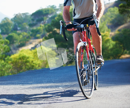 Image of Cycling, fitness and legs of man on a bicycle in road for training, wellness or sport outdoor. Health, exercise or male athlete on a bike in a street for morning cardio, workout or marathon challenge