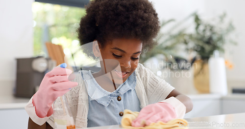 Image of Happy black girl, cleaning table and housekeeping for hygiene, disinfection or chores at home. African female person, child or kid wiping surface, furniture or kitchen in bacteria or germ removal