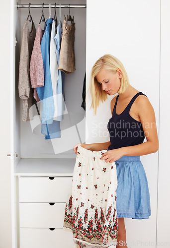 Image of Woman, decision or choosing clothes in closet for morning routine, fashion or clothing in bedroom of home. Person, outfit selection or search for skirt, garment idea or style in wardrobe or apartment