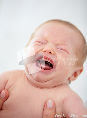 Image of Closeup, baby and crying for upset in home for pain, unhappy or sadness with mother. Woman, hand and holding of infant for bath time, diaper or change in nursery for hygiene, health or cleanliness