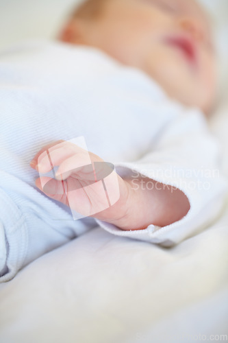 Image of Closeup, baby or new born with hand on bed for love, caring and support in home. Infant, hope and milestone for future, growth or child development with trust for bonding, protection and security