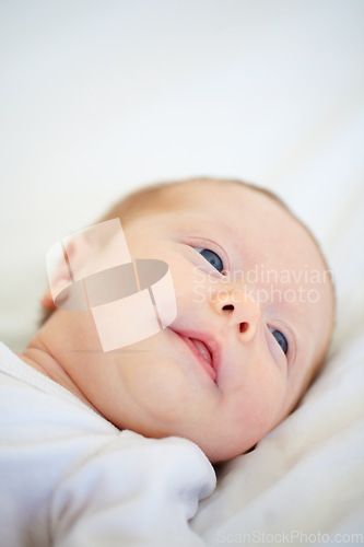 Image of Closeup, baby and face for wake up on bed from good dream, sleep or nap in nursery. Infant, looking and relaxing on pillow for child growth, cognitive and development in hope for milestone of future