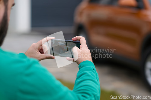 Image of man taking photos on a smartphone of a car preparing for sale