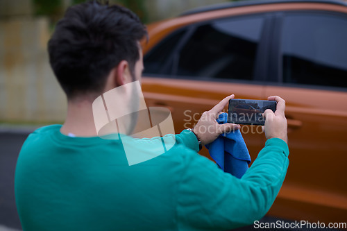 Image of man taking photos on a smartphone of a car preparing for sale