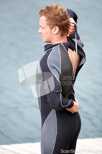 Image of Man, ready and wetsuit at lake, outdoor and extreme sports for fitness, exercise and workout. Person, swimsuit and thinking by river, nature and safety with ideas, health and start summer training