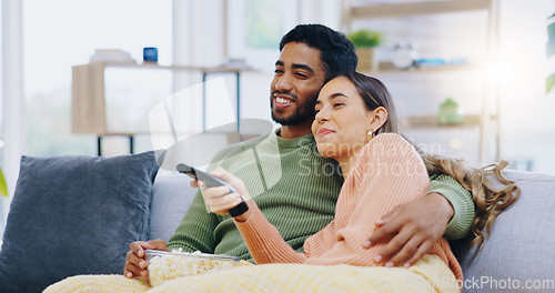 Image of Couple, watching tv and popcorn on living room sofa for smile, hug or relax with remote for choice, show or film. Man, woman and happy together for embrace, movie or streaming on lounge couch in home