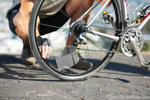 Image of Check, wheel and hand on bicycle with road, street and outdoor exercise with flat tire. Cycling, athlete and closeup on safety, inspection and test for bike with person on asphalt with pedal or gears
