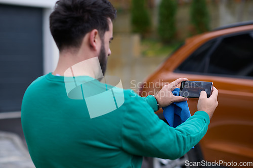 Image of man taking photos on a smartphone of a car preparing for sale
