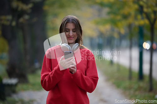 Image of Sporty woman checks smartphone before doing some exercises listens music from a playlist