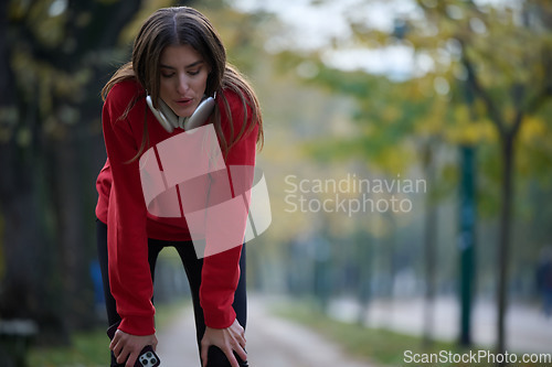 Image of Athletic young woman taking a breath and relaxing after jogging and stretching. Woman Training and Workout Exercises On Street.