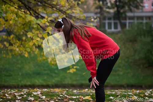 Image of Athletic young woman taking a breath and relaxing after jogging and stretching. Woman Training and Workout Exercises On Street.