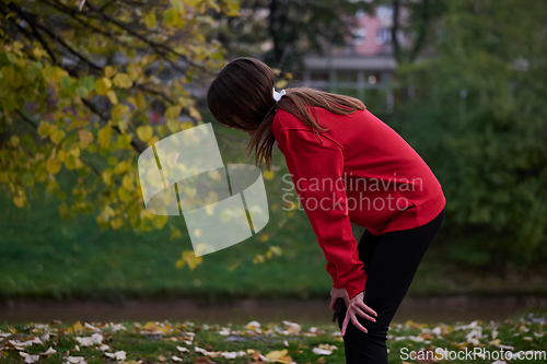 Image of Athletic young woman taking a breath and relaxing after jogging and stretching. Woman Training and Workout Exercises On Street.