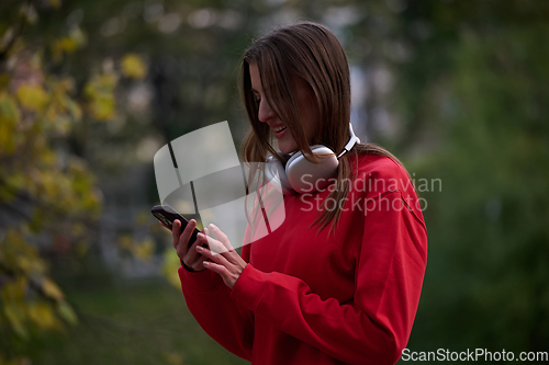 Image of Sporty woman checks smartphone before doing some exercises listens music from a playlist