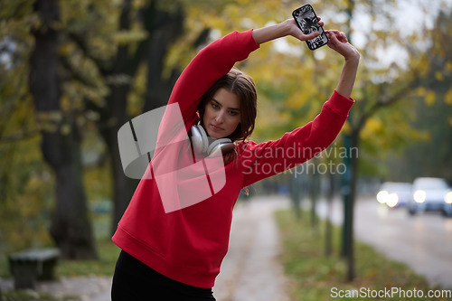 Image of Athletic young woman taking a breath and relaxing after jogging and stretching. Woman Training and Workout Exercises On Street.