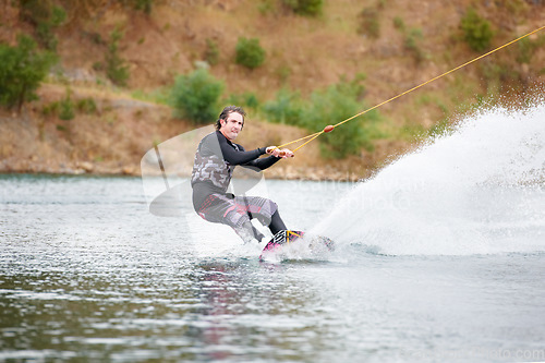 Image of Spray, wakeboarding and adventure, man on lake with outdoor fun, fitness and wave splash. Balance, water sports and person on river with freedom, speed and energy for surfing challenge, ski and trick