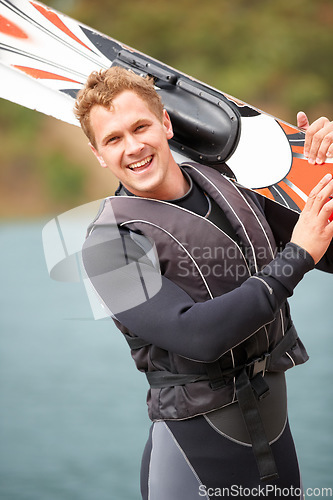 Image of Sports, portrait and man by water with wakeboard for surfing, exercise and recreation hobby by lake. Fitness, extreme sport and excited person with skiing board for freedom, adventure and outdoor fun