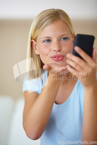 Image of Blow kiss, smartphone and video call with woman, social media and influencer live streaming in a lounge. Home, person or girl with cellphone, online followers and internet with post, app or happiness