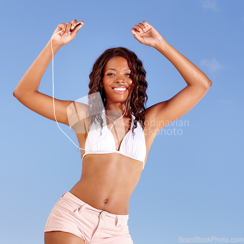Image of Black woman, dancing and bikini portrait with holiday and travel from happy audio and headphones in studio. Smile and music with freedom and vacation of African female person with blue background