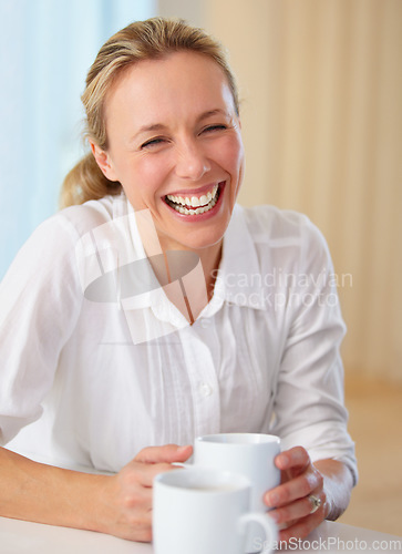 Image of Happy mature woman, laughing and coffee for funny joke, conversation or humor on kitchen table at home. Blonde female person smile or laugh with cup of tea for meme, discussion or fun chat at house