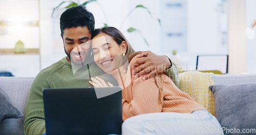 Image of Couple, love and smile with laptop on sofa to watch movies, comedy subscription and online shopping at home. Happy man hug interracial woman at computer to download funny multimedia show in lounge