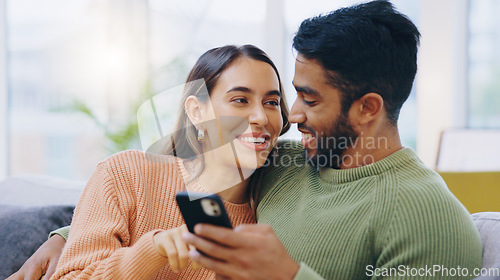 Image of Couple, phone and smile on sofa for social media, reading notification or scroll online shopping app at home. Happy man, interracial woman or smartphone to search digital news, mobile blog or website