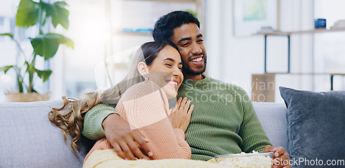 Image of Love, hug and couple on watching tv on a sofa with popcorn for movie, film or streaming show at home. Relax, television and people embrace in a living room with cinema snack for comedy or series
