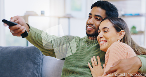 Image of Couple, watching tv and remote on living room sofa with smile, hug or relax with click for choice, show or film. Man, woman and happy together for embrace, movie or streaming on lounge couch in home