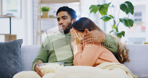 Image of Fear, hug and couple watching tv on a sofa with popcorn for movie, film or streaming show at home. Wow, television and people embrace in living room with cinema snack for omg, horror or spooky series