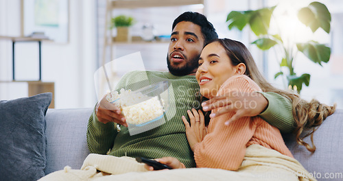 Image of Fear, hug and couple watching tv with popcorn on a sofa for movie, film or streaming show in their home. Wow, television and people embrace in a living room with cinema snack for horror or series