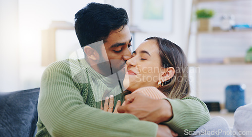 Image of Kiss, hug and couple on a sofa with love, relax and security at home bonding, hanging out or chilling. Happy, support and people in a living room with trust, commitment and gratitude, care or romance