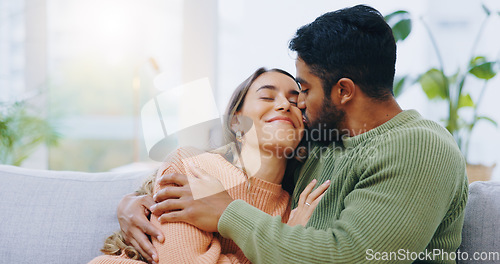 Image of Hug, kiss and couple on a sofa with love, relax and security at home bonding, hanging out or chilling. Happy, support and people in a living room with trust, commitment and gratitude, care or romance