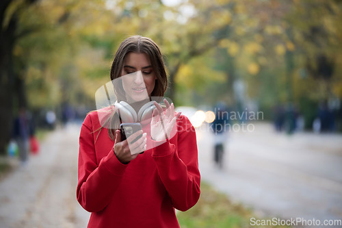 Image of Sporty woman checks smartphone before doing some exercises listens music from a playlist