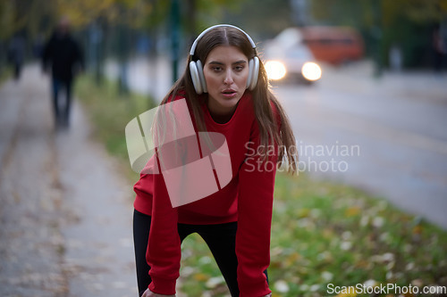 Image of Athletic young woman taking a breath and relaxing after jogging and stretching. Woman Training and Workout Exercises On Street.