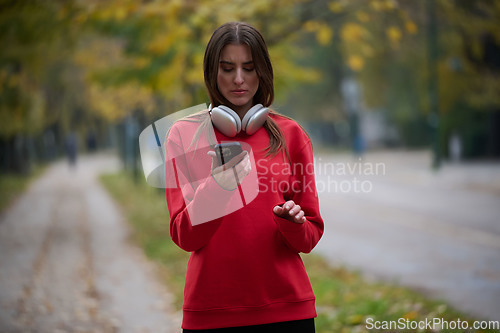 Image of Sporty woman checks smartphone before doing some exercises listens music from a playlist