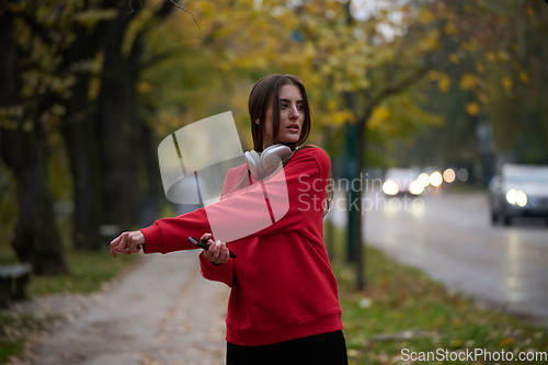 Image of Athletic young woman taking a breath and relaxing after jogging and stretching. Woman Training and Workout Exercises On Street.