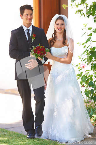 Image of Happy couple, wedding and holding hands with roses for marriage, love or outdoor commitment together. Married bride and groom walking with smile and bouquet of flowers at bridal event or ceremony
