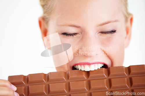 Image of Studio face, woman or eating chocolate bar, delicious snack or candy for unhealthy food, dessert or sugar product. Diet craving, calories or girl bite, taste or enjoy cacao sweets on white background