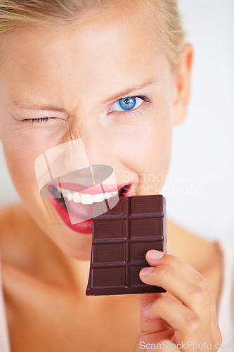 Image of Portrait, woman wink and eating chocolate bar, delicious snack or candy for studio food, dessert or sugar product. Diet craving, cacao sweets or girl face with cheat meal isolated on white background