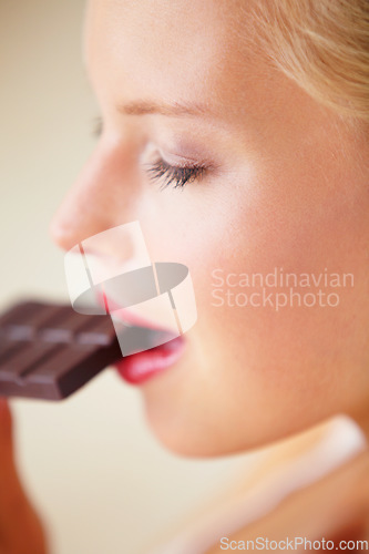 Image of Relax woman face, eating and bite chocolate bar, tasty cocoa snack or unhealthy junk food for wellness, stress relief or craving. Head profile, antioxidant product benefits and girl enjoy cacao slab