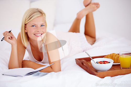 Image of Woman, bed and notebook with breakfast, portrait and happy with smile, bedroom for journaling. Food, fruits and croissant with orange juice, nutrition and healthy diet in home, rest and cheerful