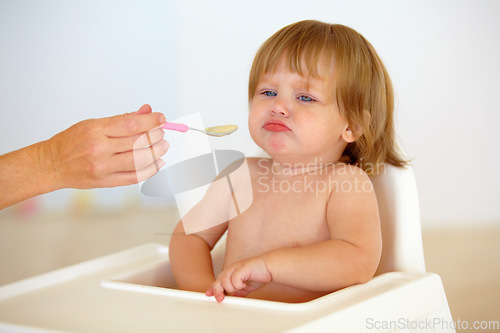 Image of Baby, chair and eating food or unhappy mood for health meal, childhood development or upset. Hand, spoon and feed seat or tired fail kid for dinner or disappointed face or distress, care or problem