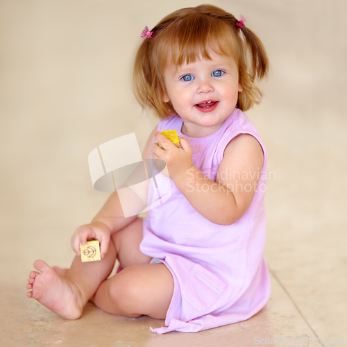 Image of Portrait, toddler or little girl with toy in home for motor skills, child development or growth. Happy kid, cute and trendy hairstyle with hand holding for block for grip with milestone for future